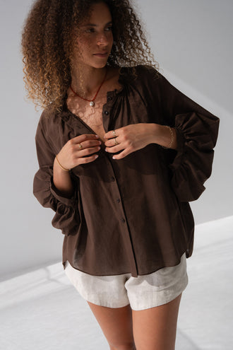 Thalia Cotton Voile Shirt in Chocolate - close-up, gathered neckline and button-front detail, balloon sleeves, worn over Gaia Linen Shorts in Oatmeal - Lilly Pilly Collection