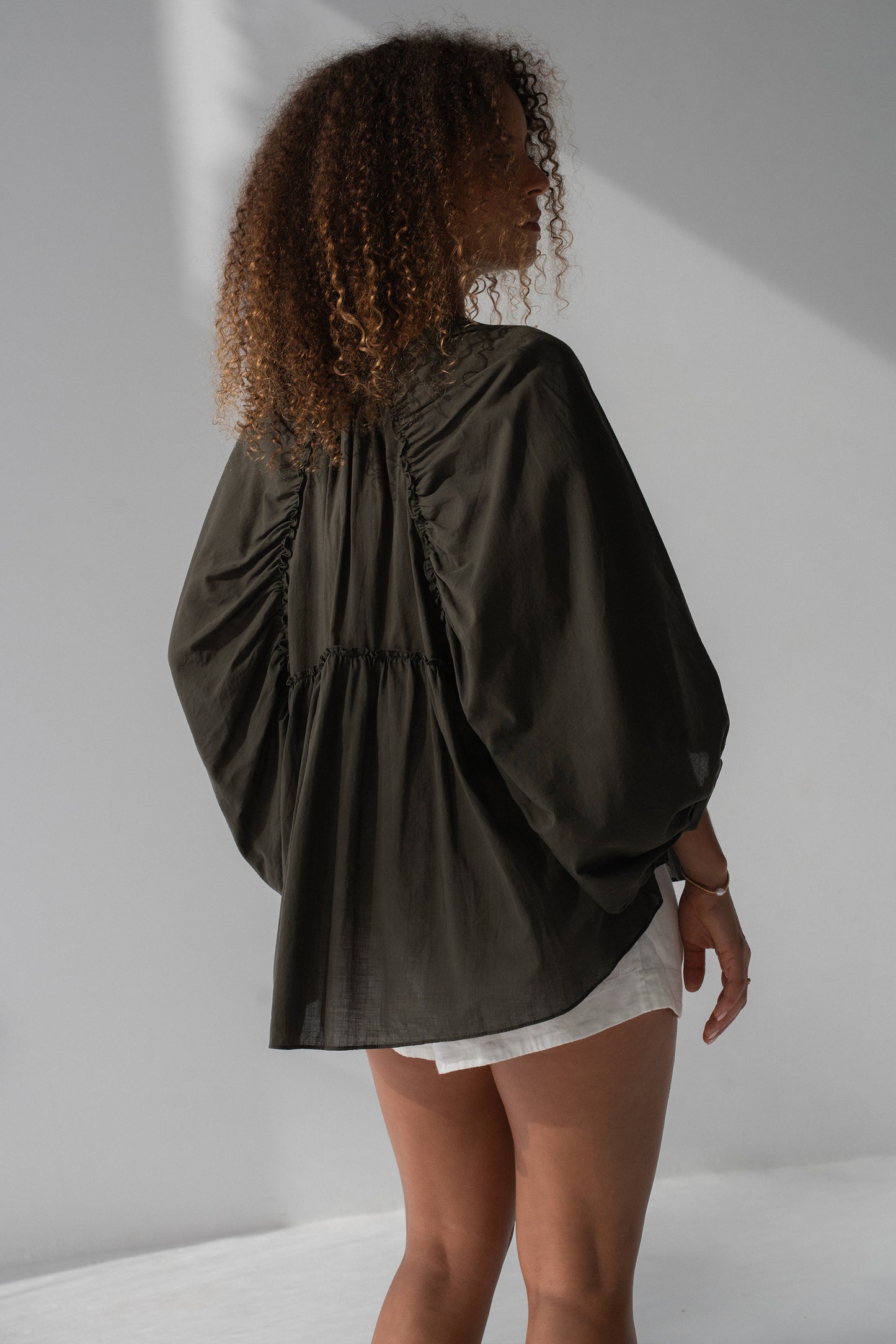 Thalia Cotton Voile Shirt in Khaki - back view, gathered back yoke and balloon sleeves, worn with white shorts - Lilly Pilly Collection