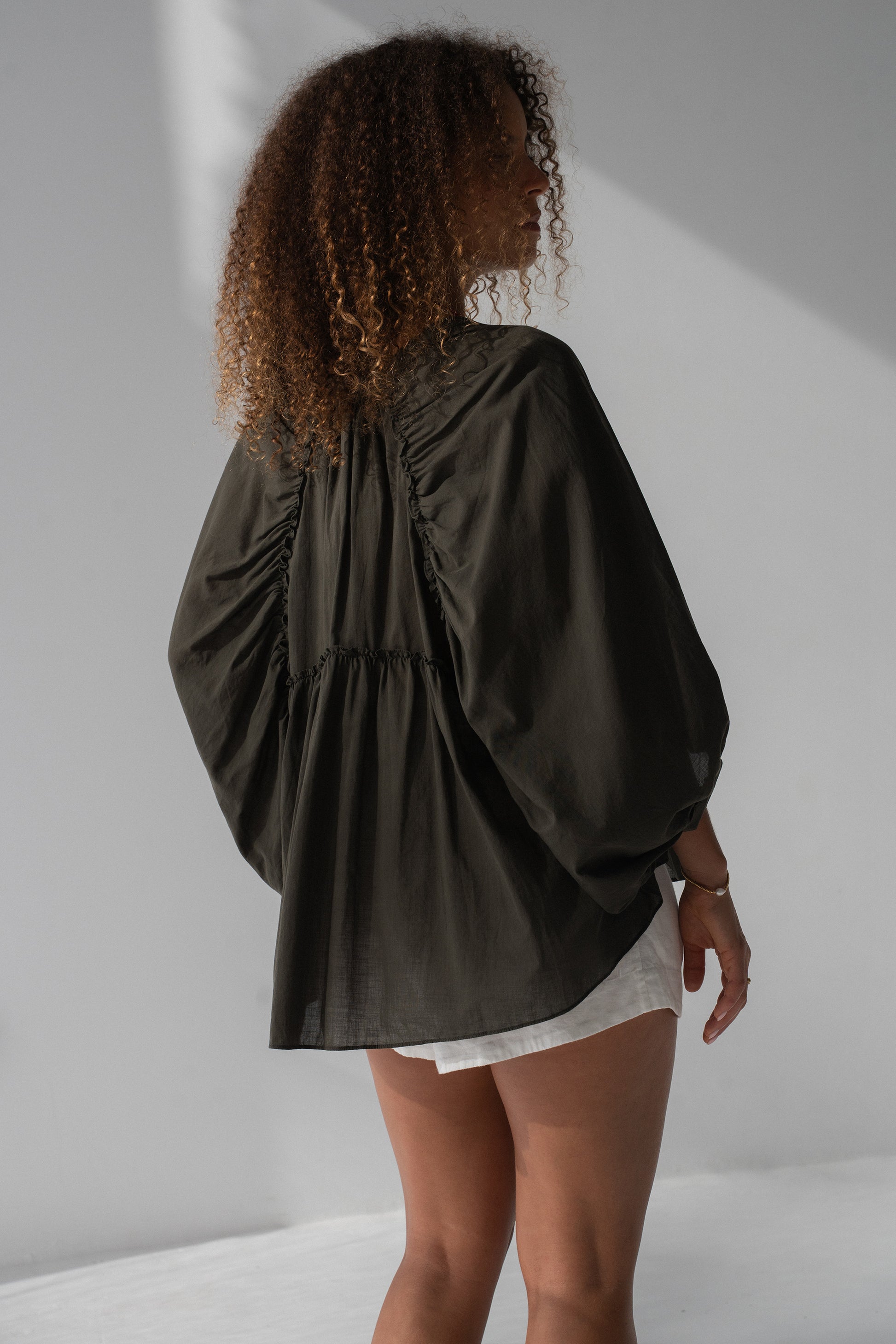 Thalia Cotton Voile Shirt in Khaki - back view, gathered back yoke and balloon sleeves, worn with white shorts - Lilly Pilly Collection