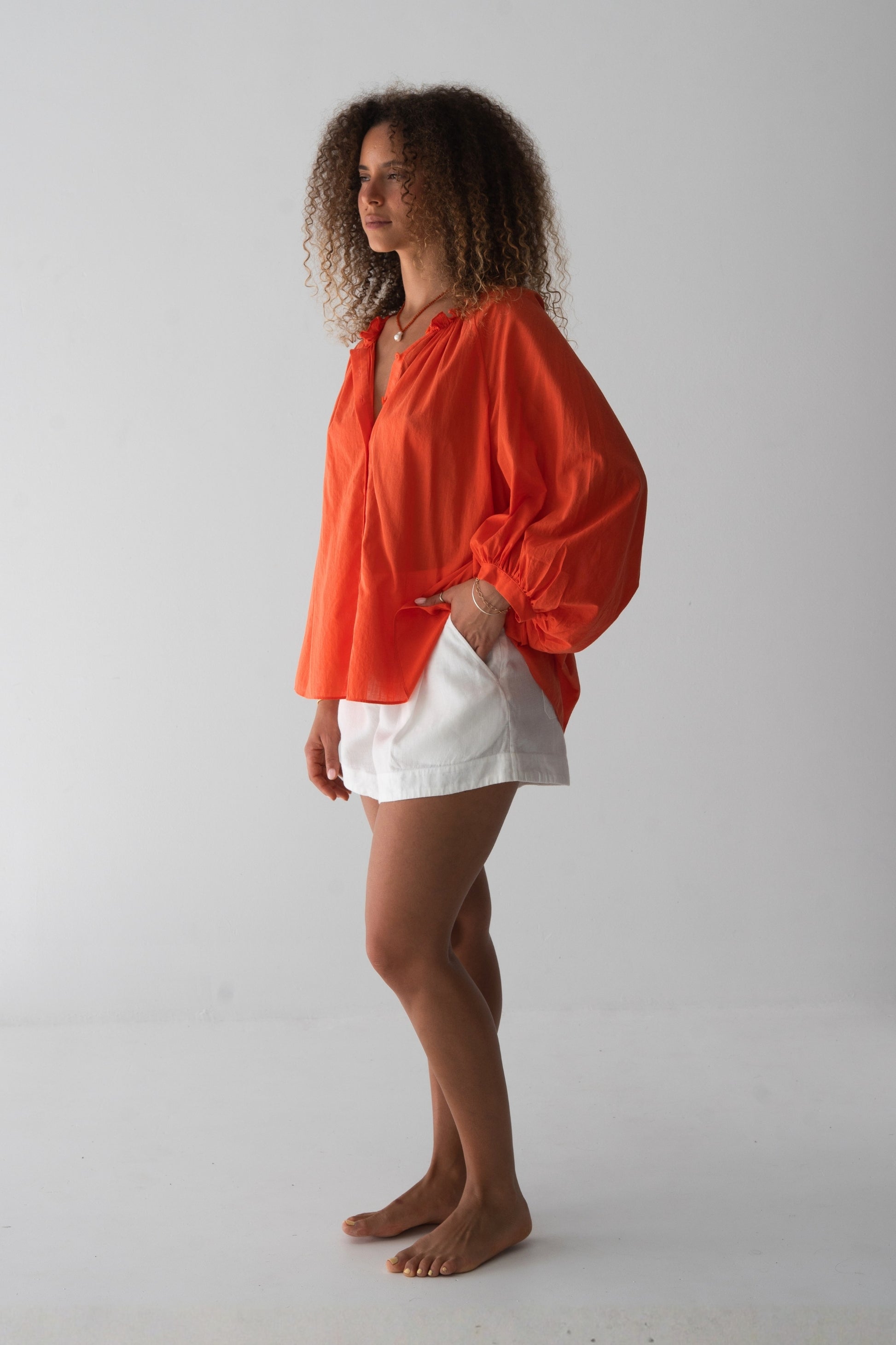 Thalia Cotton Voile Shirt in Spritz Orange - side view, gathered neckline and balloon sleeves, worn open over white linen shorts - Lilly Pilly Collection