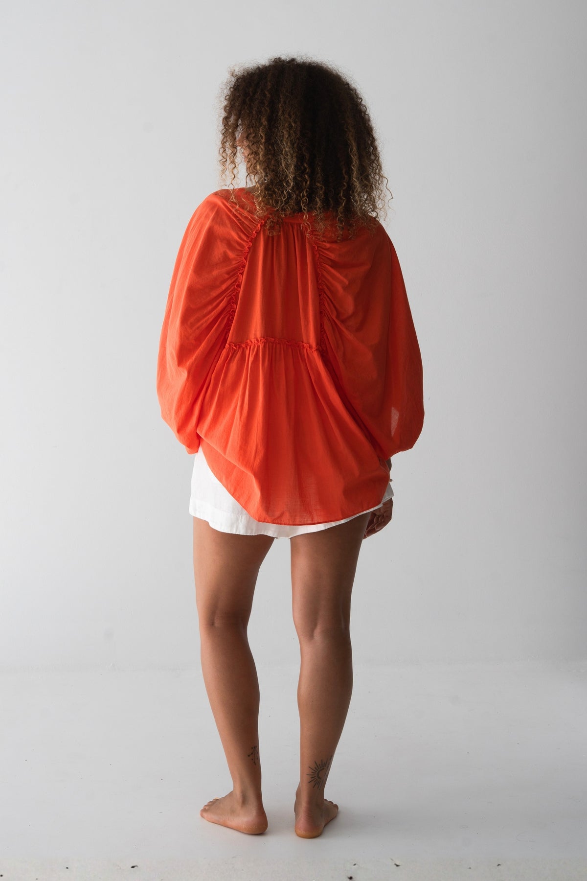 Thalia Cotton Voile Shirt in Spritz Orange - back view, gathered back yoke and balloon sleeves, worn open over white linen shorts - Lilly Pilly Collection