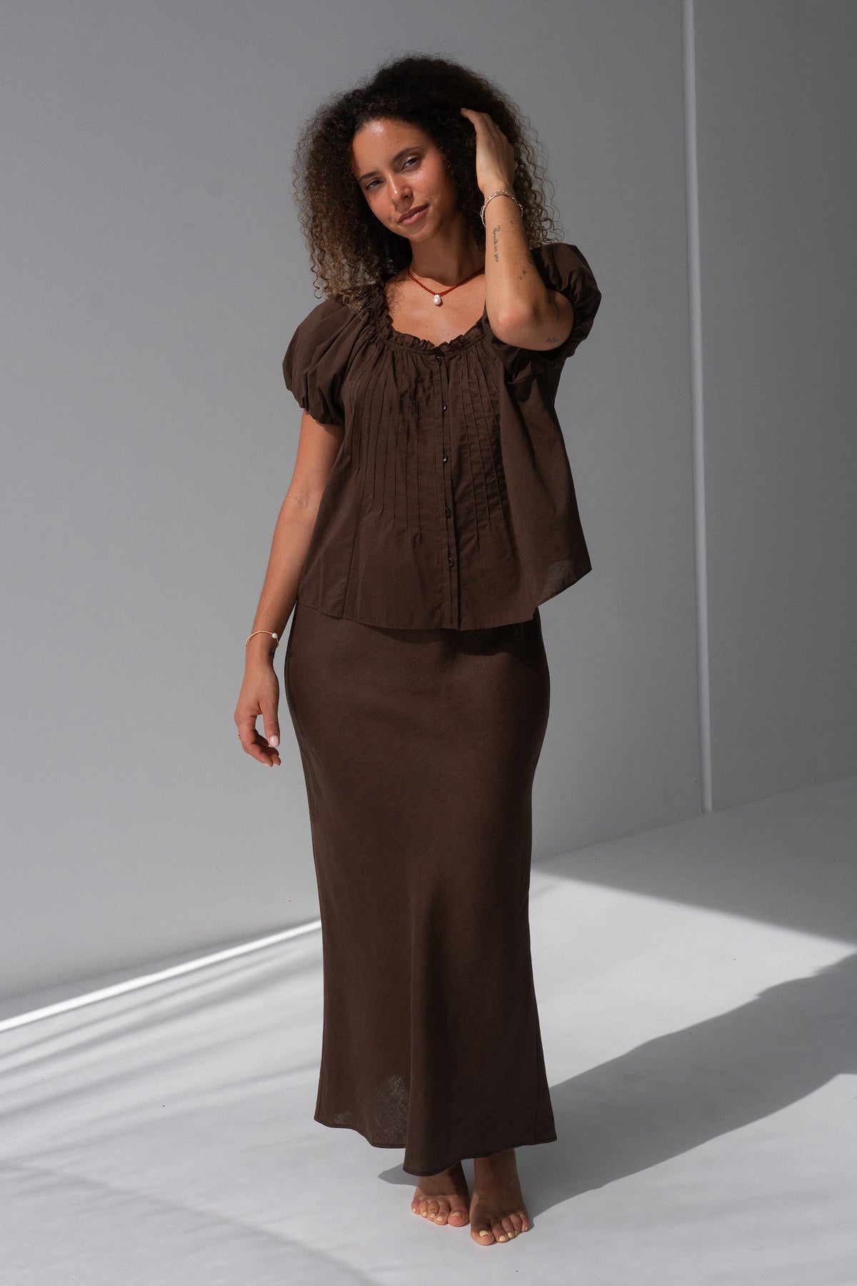 Tilly Cotton Voile Shirt in Chocolate - full length, gathered ruffle neckline and pintuck detail, puff sleeves, worn with matching Riley Bias Linen Midi Skirt in Chocolate, hand in hair - Lilly Pilly Collection