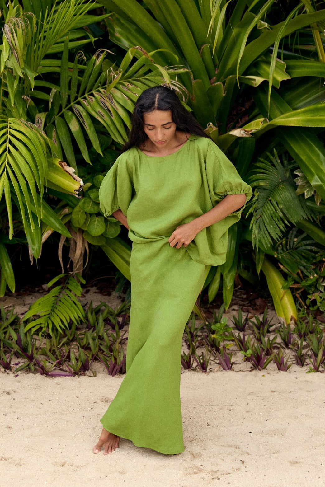 Tina Linen Top in Lime Green - woman standing on beach, oversized puff sleeves and round neckline, styled with matching Riley Linen maxi skirt, tropical backdrop - Lilly Pilly Collection