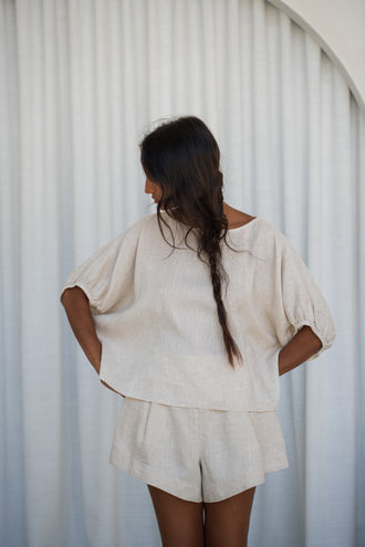 Tina Linen Top in Oatmeal - back view, hands on hips, puff sleeves and back keyhole, styled with matching Gaia Linen shorts - Lilly Pilly Collection