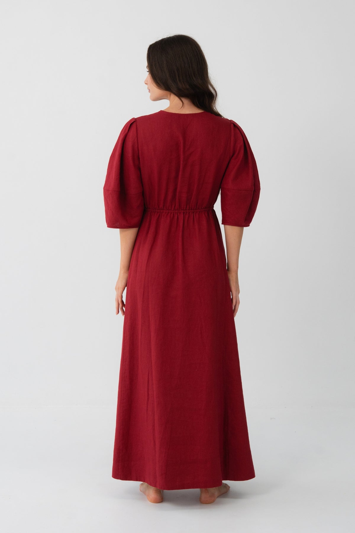 Back view of a woman wearing the Vida Linen maxi dress in Cherry Red in a studio setting - Lilly Pilly Collection