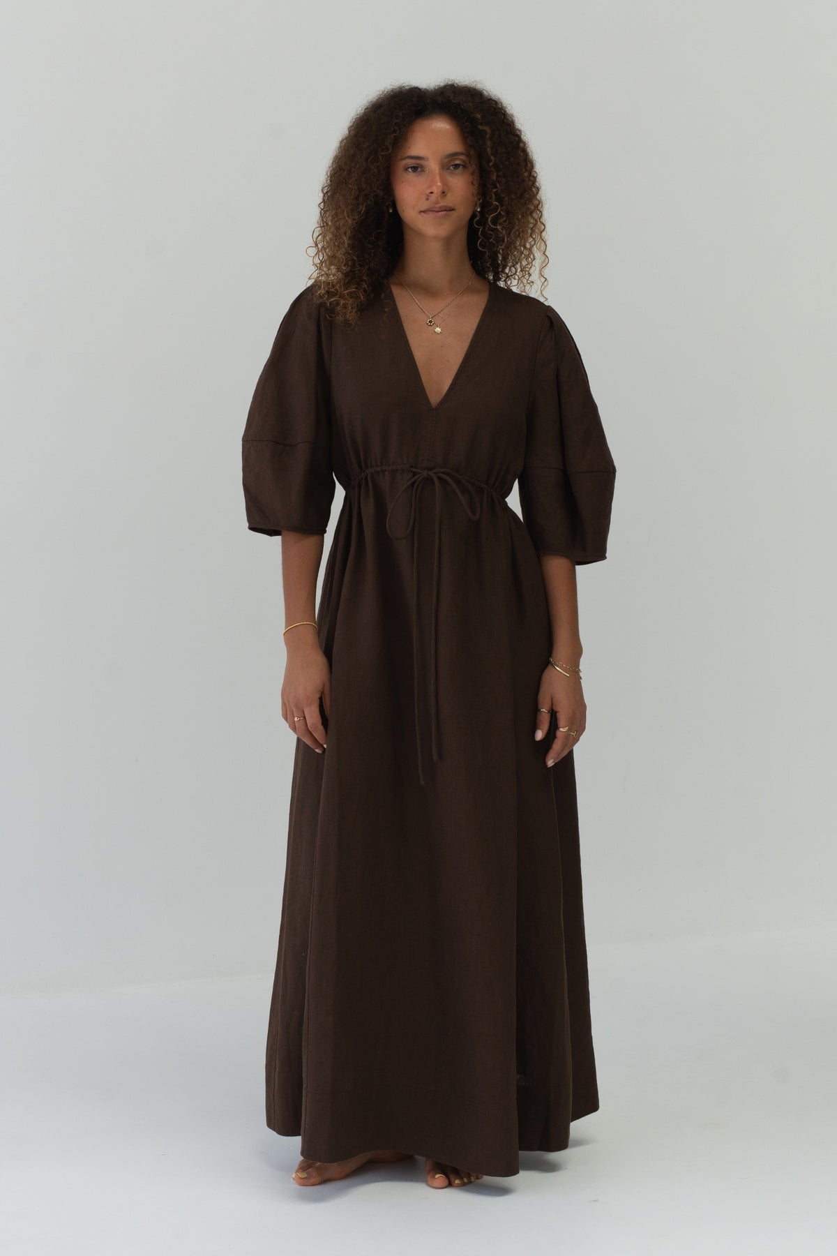Front view of a woman wearing the Vida Linen maxi dress in Chocolate in a studio - Lilly Pilly Collection