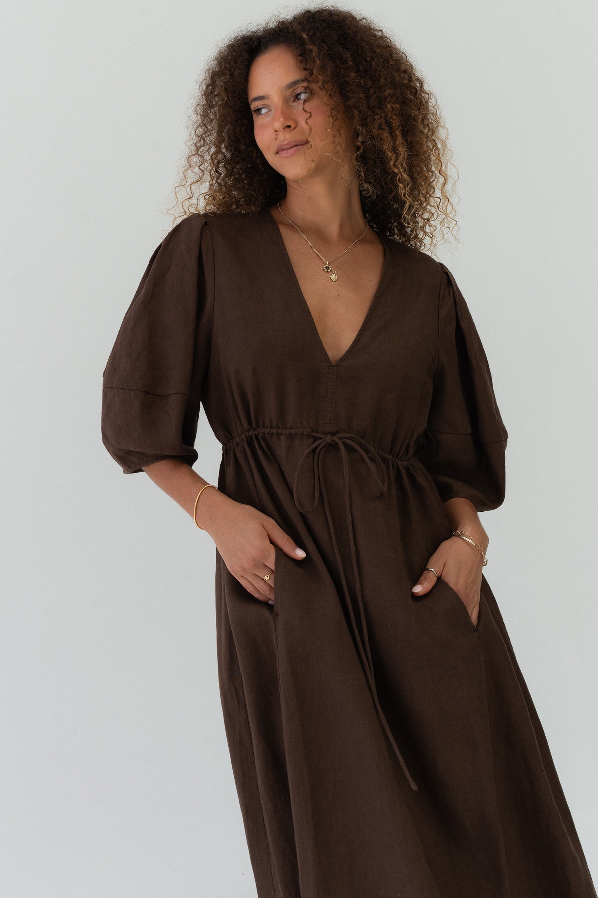Front angle view of a woman wearing the Vida Linen maxi dress in Chocolate in a studio setting - Lilly Pilly Collection