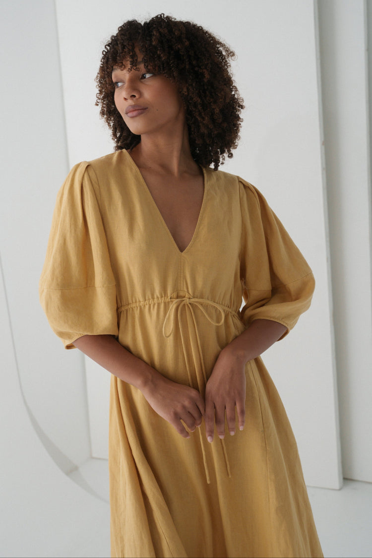 Close-up view of a woman wearing the Vida Linen maxi sleeve dress in Sand Beige - Lilly Pilly Collection
