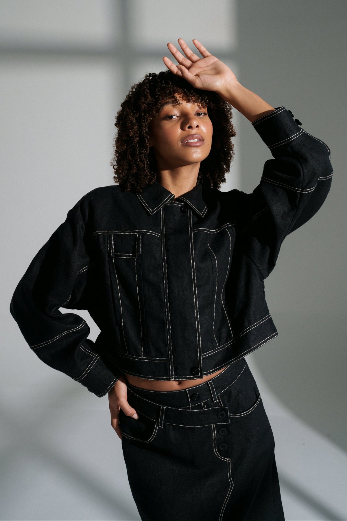 LILLY PILLY woman wearing a black Wes linen jacket against a neutral background