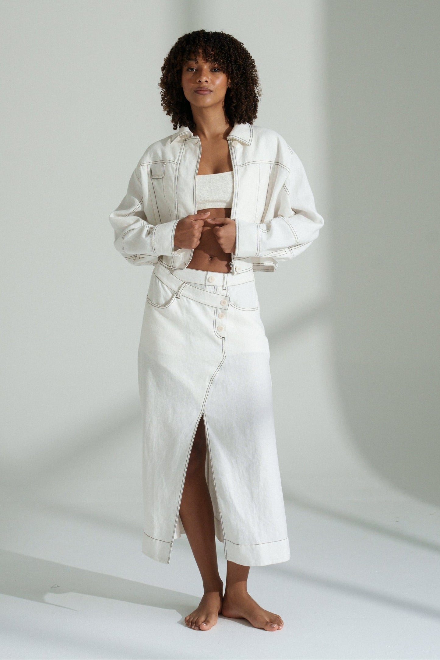 LILLY PILLY woman wearing an ivory Wes linen jacket standing against a plain background