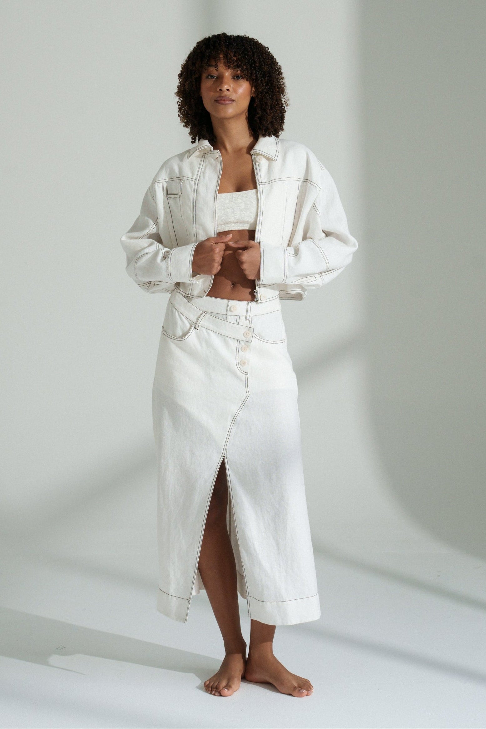 LILLY PILLY woman wearing an ivory Wes linen jacket standing against a plain background
