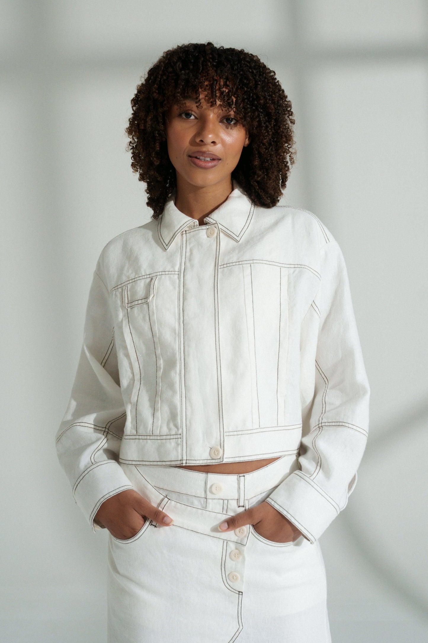 LILLY PILLY woman wearing an ivory Wes linen jacket and skirt against a light background