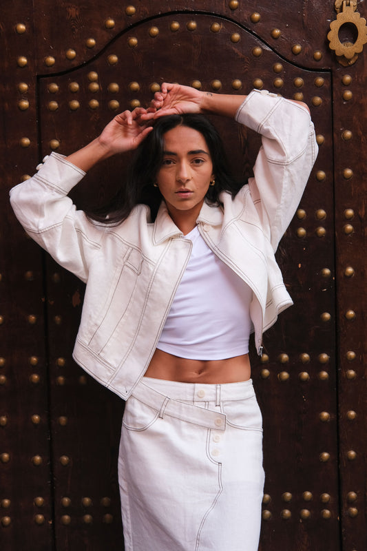 LILLY PILLY woman wearing an ivory Wes linen jacket in front of a dark wooden door with gold accents