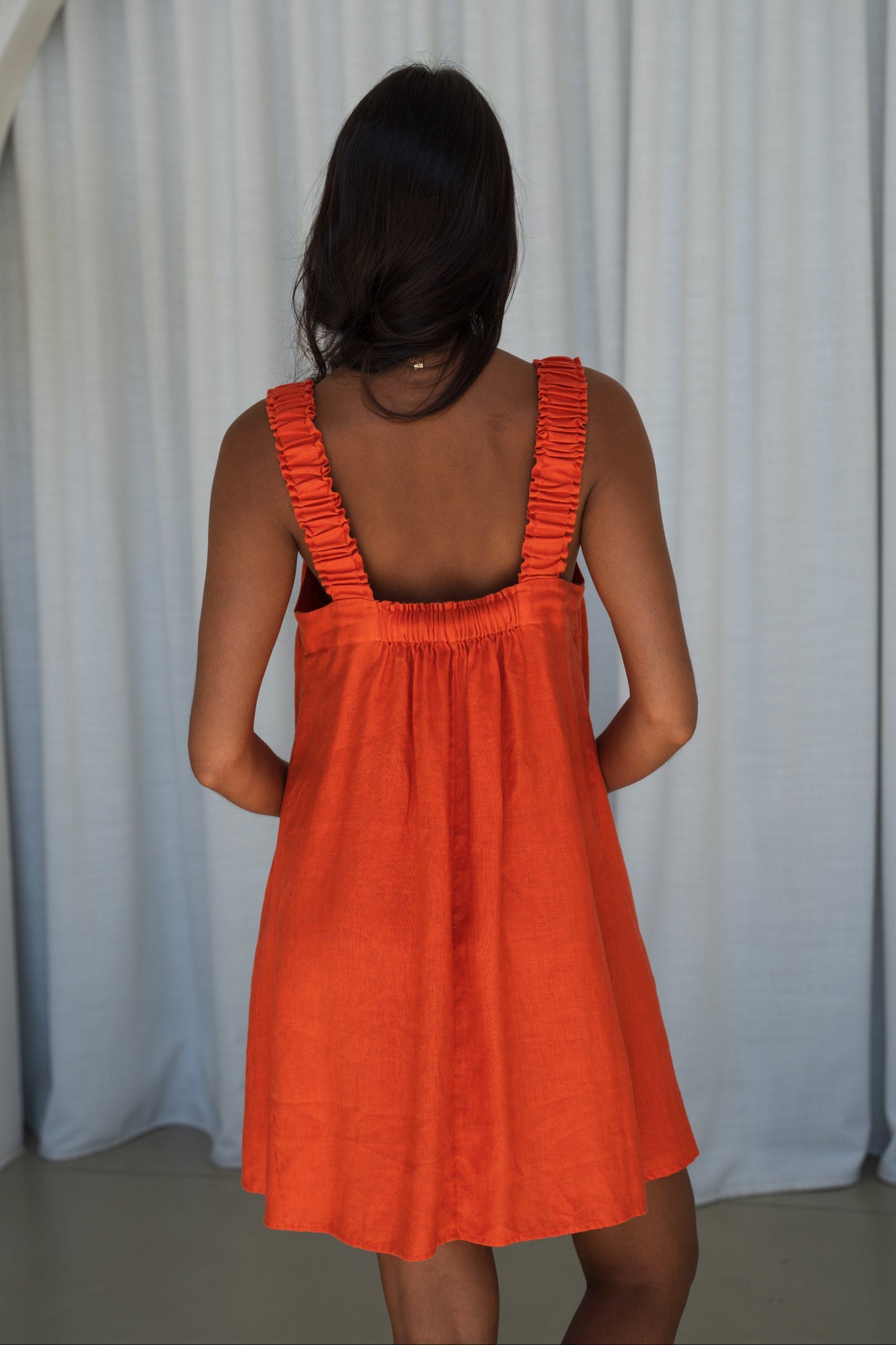 LILLY PILLY woman in an spritz Zahra linen dress showing back view while standing in front of a neutral background