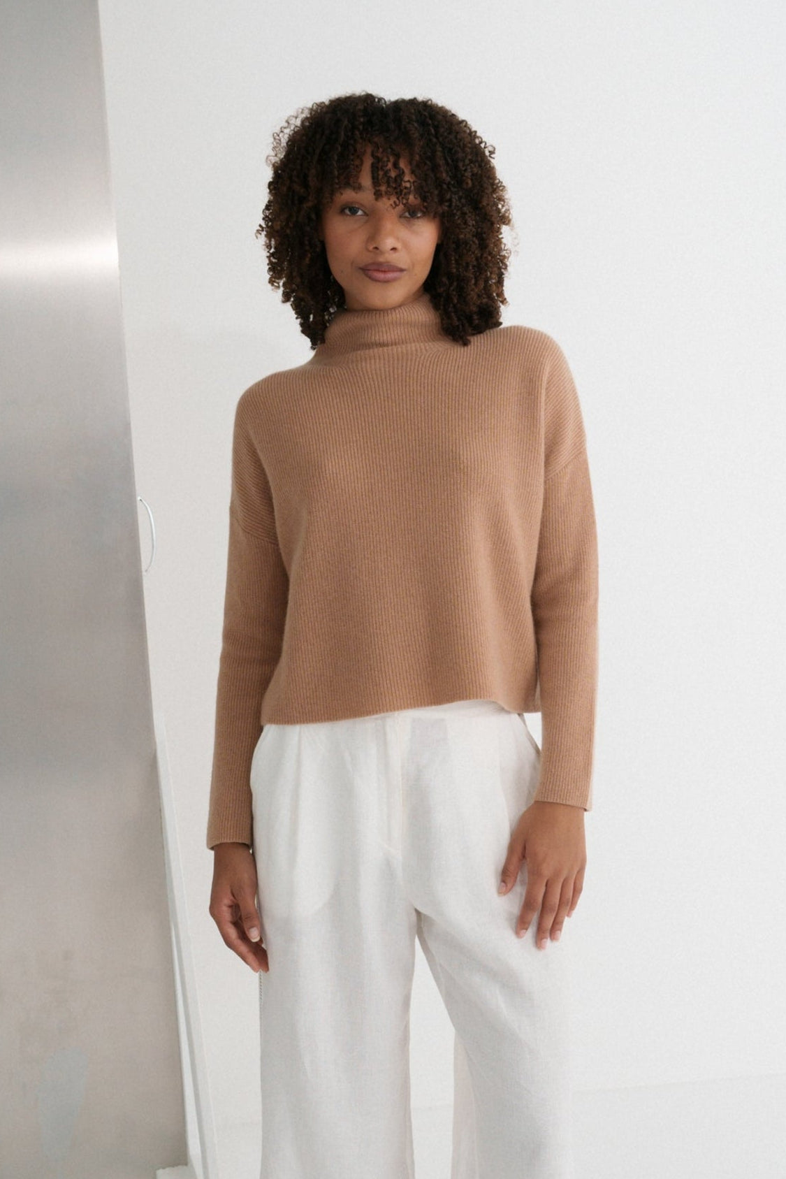 LILLY PILLY woman wearing a camel brown June cashmere knit sweater and ivory white linen pants