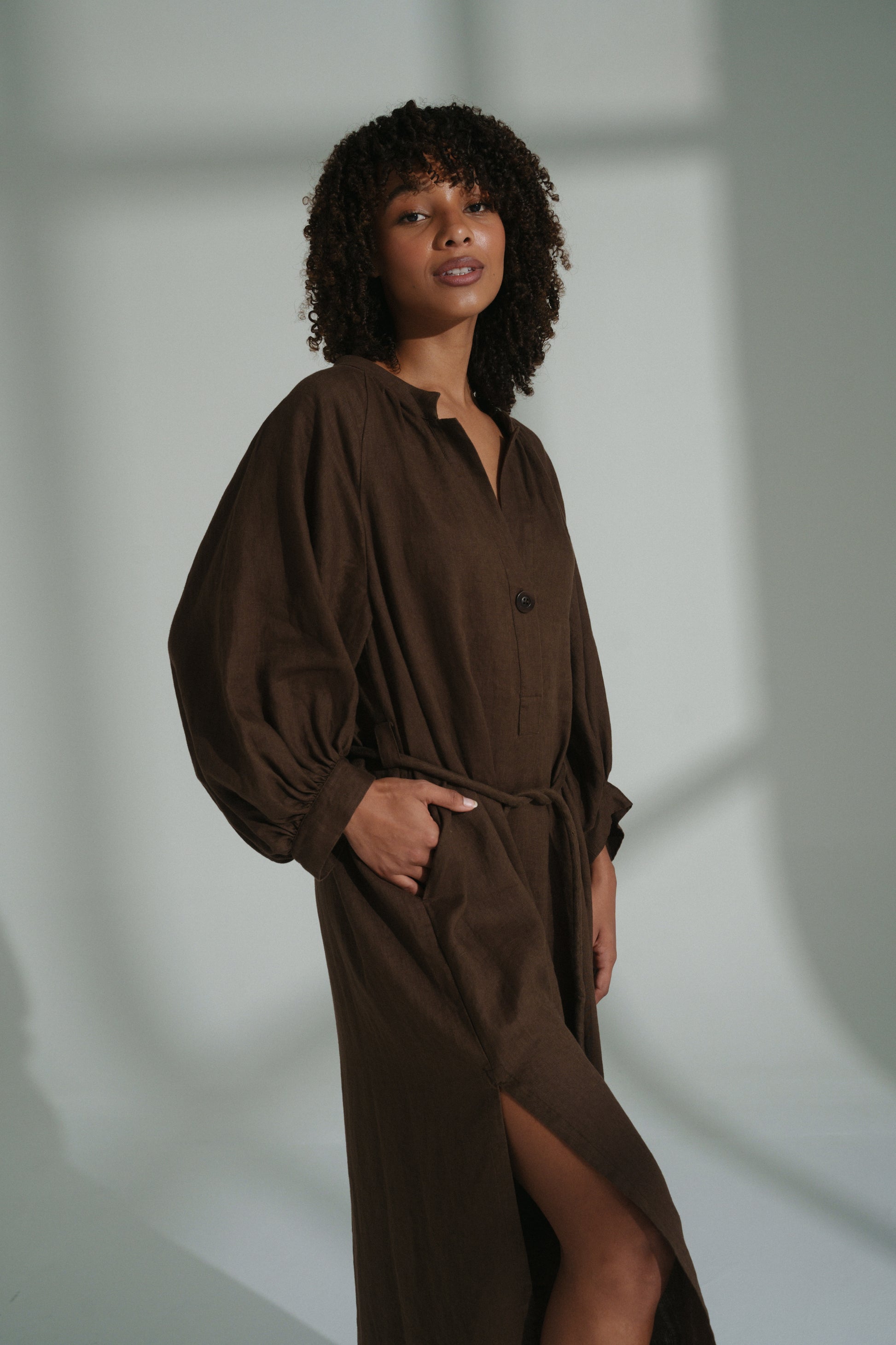 LILLY PILLY woman wearing a chocolate brown Mae linen dress standing against a neutral background