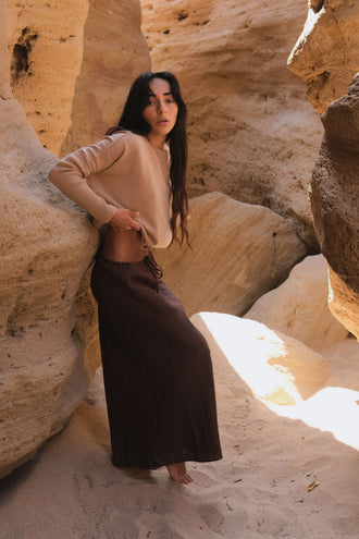 Miri Cashmere Knit in Camel Brown - side view while standing by a natural rock formation - Lilly Pilly Collection
