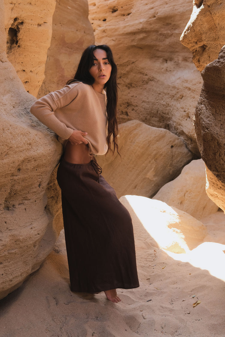 Miri Cashmere Knit in Camel Brown - side view while standing by a natural rock formation - Lilly Pilly Collection