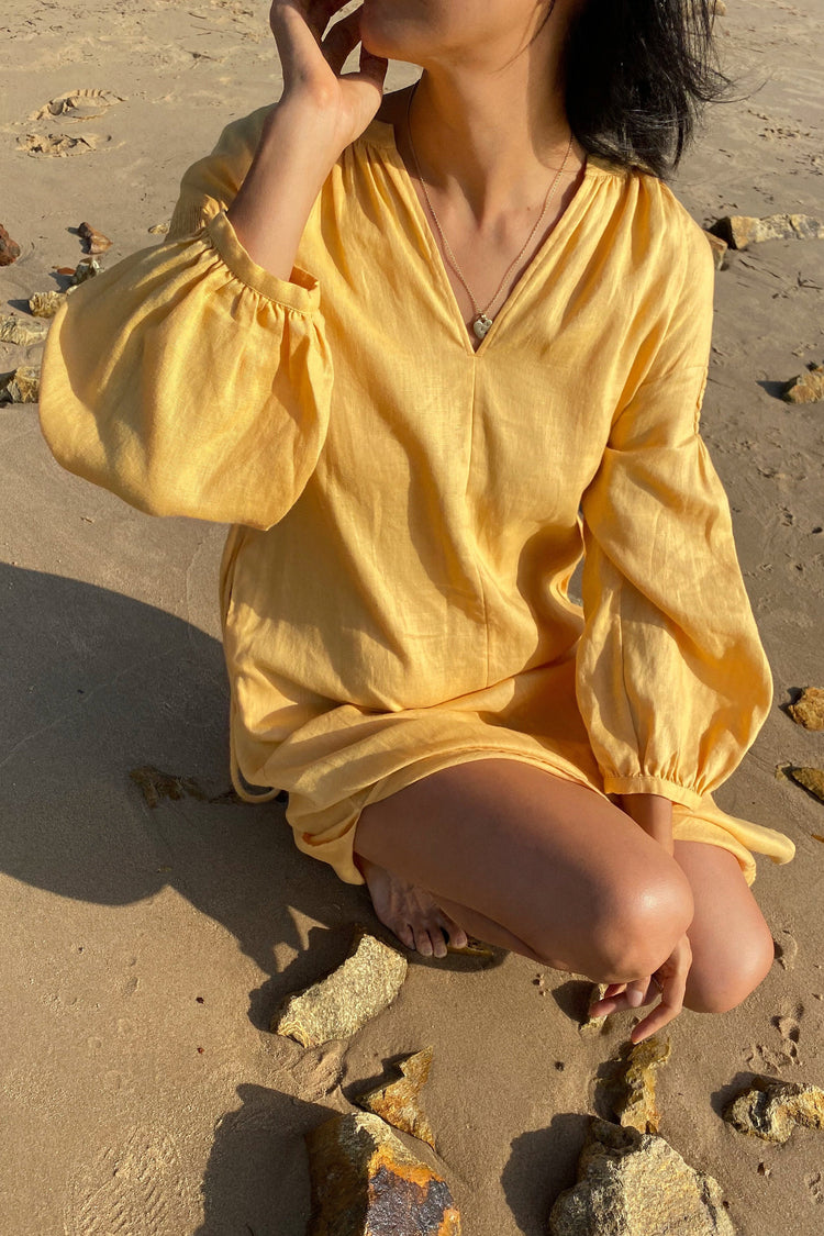 Skylar Linen Dress in Butter Yellow - front view while crouching on the beach - Lilly Pilly Collection