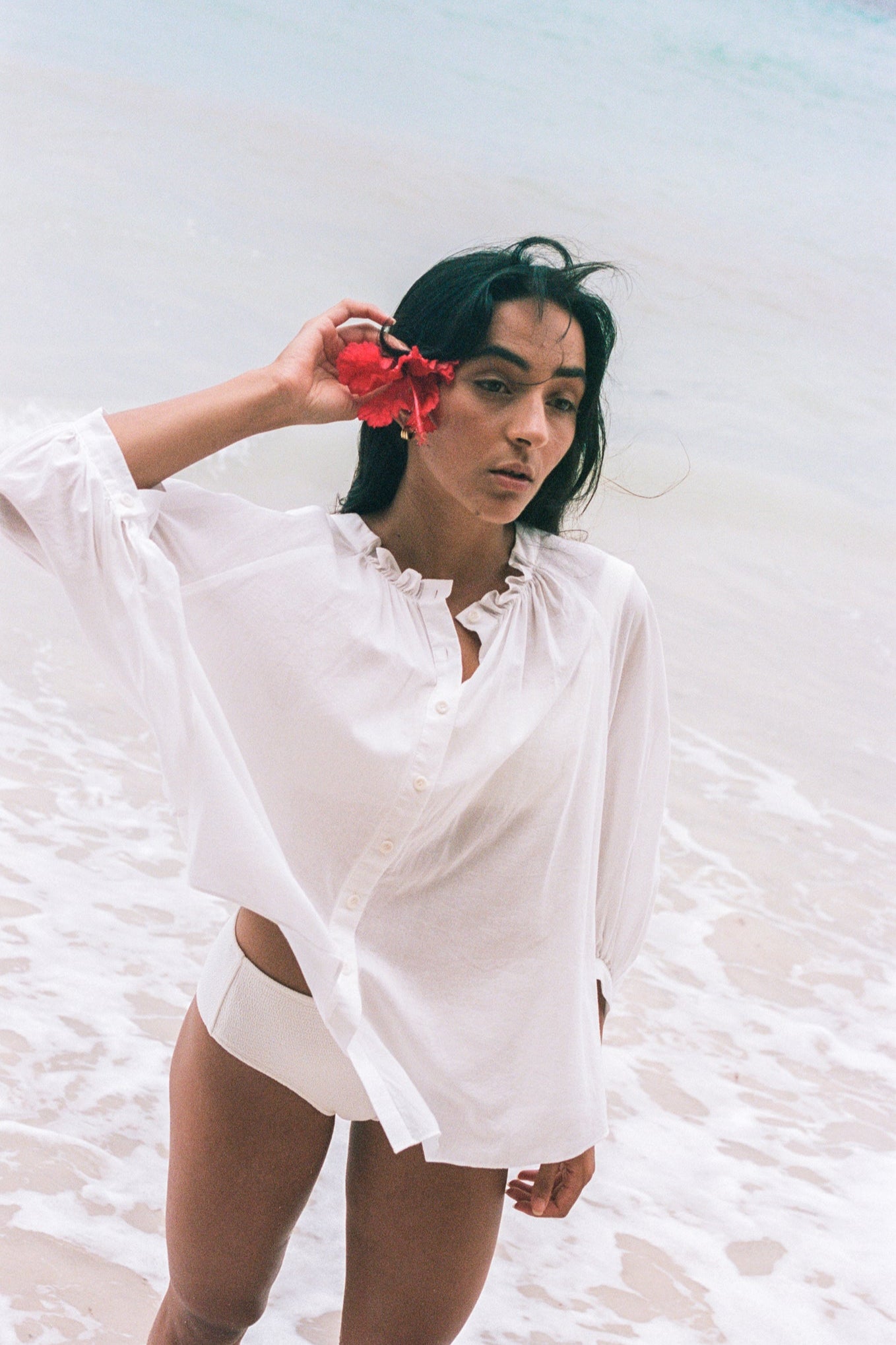 LILLY PILLY woman wearing a ivory Thalia cotton voile shirt blouse with a flower in her hair standing by the waters edge