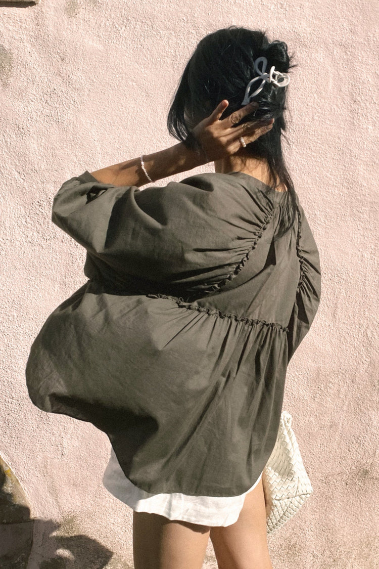 Thalia Cotton Voile Shirt in Khaki - back view, hand in hair, worn buttoned, pink wall backdrop - Lilly Pilly Collection