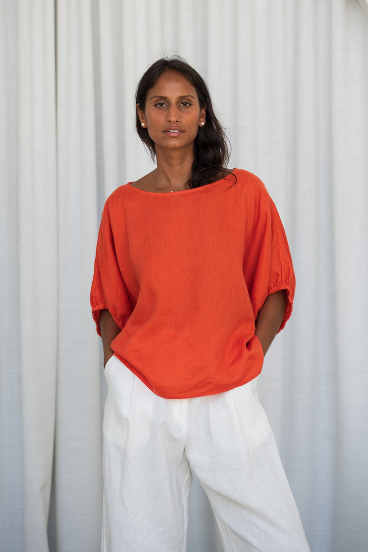 Tina Linen Top in Spritz Orange - front view, styled with ivory Oli linen pants, white curtain background - Lilly Pilly Collection